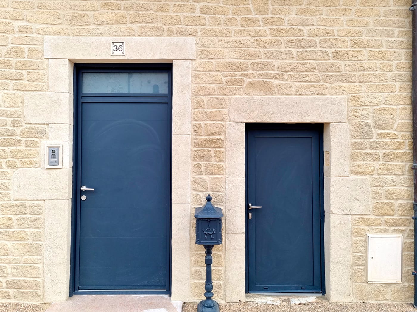 Encadrements de portes en imitation pierre de taille sur une façade en pierre jointée beige